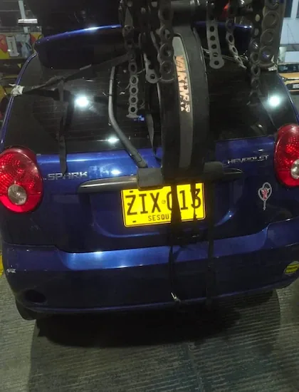 This would be the license plate of the blue Chevrolet Spark